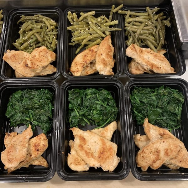 Six meal prep containers with grilled chicken and either green beans or spinach.
